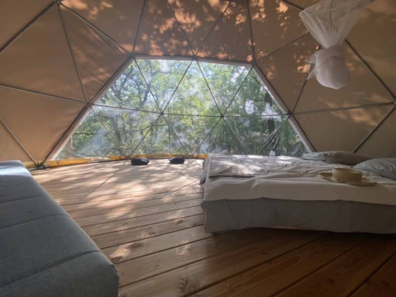 Dôme géodésique avec vue sur la nature, lit confortable et ambiance lumineuse.