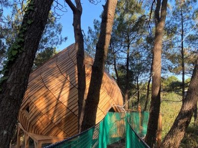 Cabane perchée en Bretagne, accessible par un pont suspendu entre les arbres.