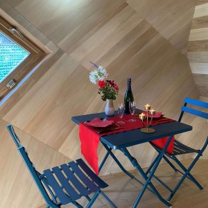 Hébergement insolite en Bretagne : intérieur en bois avec table romantique et vue sur la nature.