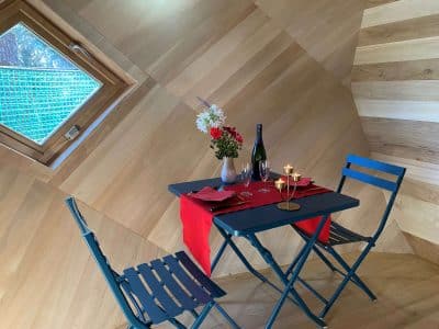 Hébergement insolite en Bretagne : intérieur en bois avec table romantique et vue sur la nature.