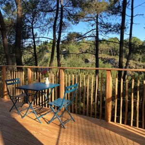 Cabane perchée en Bretagne avec terrasse en bois et vue sur la forêt verdoyante.