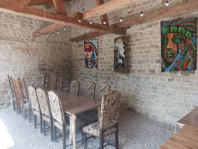 Hébergement insolite à Champagne-Ardenne : salle à manger avec murs en pierre et œuvres colorées.