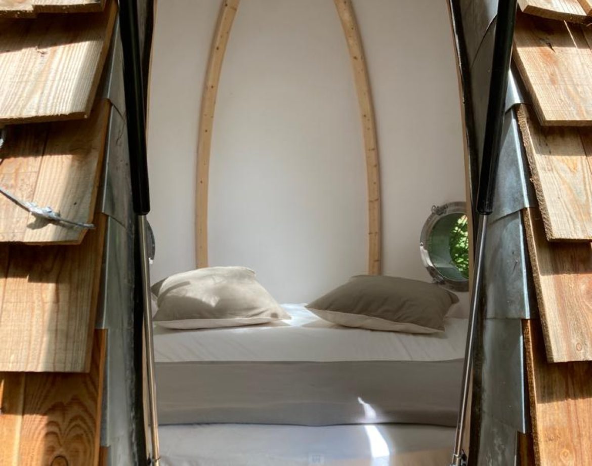 Hébergement insolite en forme de cocon avec un lit confortable et des murs en bois.