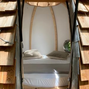 Hébergement insolite en forme de cocon avec un lit confortable et des murs en bois.