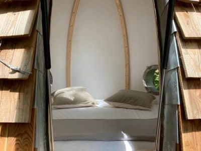 Hébergement insolite en forme de cocon avec un lit confortable et des murs en bois.