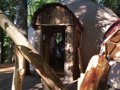 Dôme en bois dans les arbres, offrant une expérience unique en pleine nature.