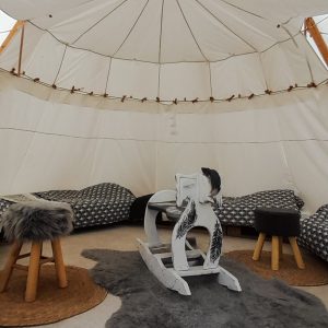 Tente tipi cosy à Champagne-Ardenne, avec fauteuils moelleux et tapis en fourrure.