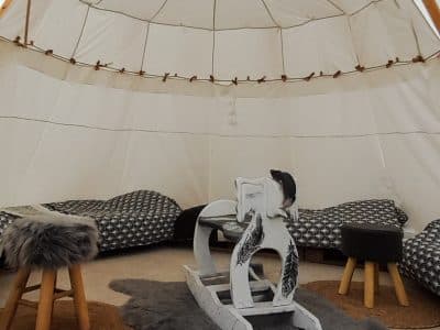 Tente tipi cosy à Champagne-Ardenne, avec fauteuils moelleux et tapis en fourrure.