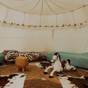 Tente safari cosy à Champagne-Ardenne, avec tapis en jute et cheval à bascule.