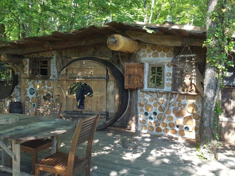 Hébergement insolite en bois à Limousin, avec une façade en rondins et un coin repas extérieur.
