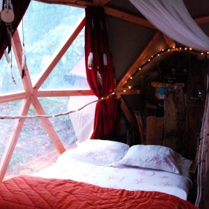 Cabane en bois au Limousin, lit douillet avec vue sur la nature et décoration chaleureuse.