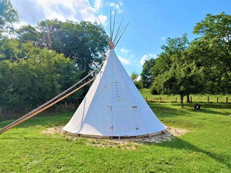 Teepee insolite à Champagne-Ardenne, entouré de verdure et sous un ciel bleu.