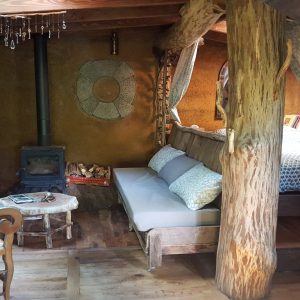 Hébergement insolite en Limousin : cabane en bois avec lit douillet et poêle à bois.