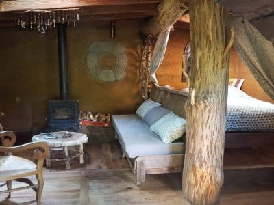 Hébergement insolite en Limousin : cabane en bois avec lit douillet et poêle à bois.