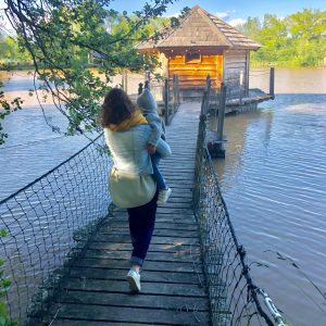 Cabane sur pilotis au bord de leau, accessible par un pont en bois. Moment paisible en famille.
