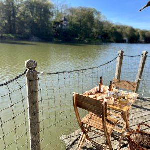 Table en bois sur pilotis au bord dun lac, hébergement insolite en Auvergne-Rhône-Alpes.