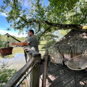 Cabane perchée en Auvergne-Rhône-Alpes, avec vue sur un lac et un panier suspendu.