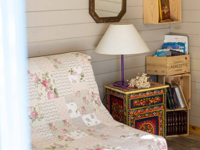 Chalet cosy avec un canapé fleuri et une lampe colorée, ambiance chaleureuse.