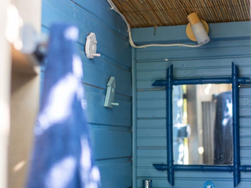 Cabane en bois avec murs bleus et lavabo moderne, ambiance chaleureuse et accueillante.
