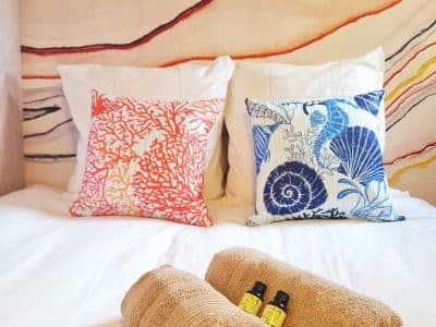 Chambre cosy dans un hébergement insolite, avec coussins colorés et serviettes douces.