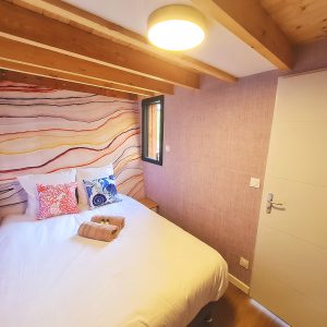 Chambre cocooning en bois avec murs colorés, idéale pour un séjour en Bourgogne-Franche-Comté.