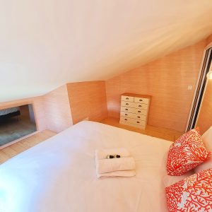 Chambre cocooning en bois avec lit douillet et coussins colorés à Bourgogne-Franche-Comté.