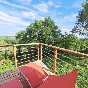 Cabane perchée en Bourgogne-Franche-Comté avec vue dégagée et chaises longues.