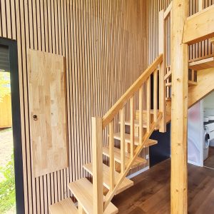Escapade en cabane en bois, intérieur chaleureux avec escaliers en bois clair.