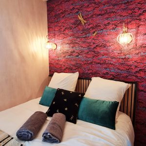 Chambre cocooning dans un hébergement insolite, mur coloré et luminaires élégants.