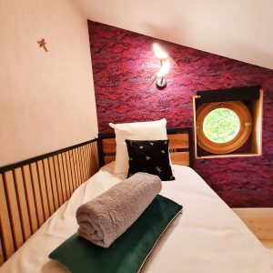 Chambre insolite en Bourgogne-Franche-Comté, décor coloré et fenêtre ronde.