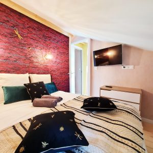 Chambre cosy dans un hébergement insolite, avec mur en briques rouges et coussins décoratifs.