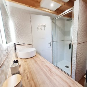 Salle de bain moderne dun hébergement insolite en Bourgogne-Franche-Comté, avec douche vitrée.