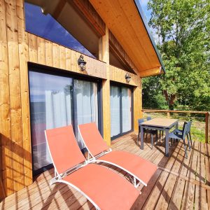 Chalet en bois avec terrasse, chaises longues et vue sur la nature en Bourgogne-Franche-Comté.