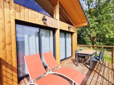 Chalet en bois avec terrasse, chaises longues et vue sur la nature en Bourgogne-Franche-Comté.