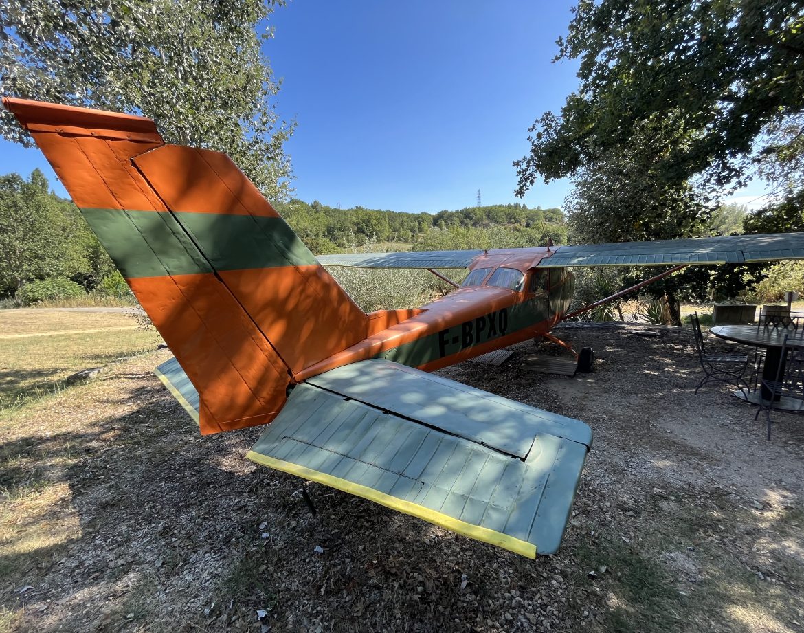 Hébergement insolite dans un avion coloré, entouré de verdure en Languedoc-Roussillon.