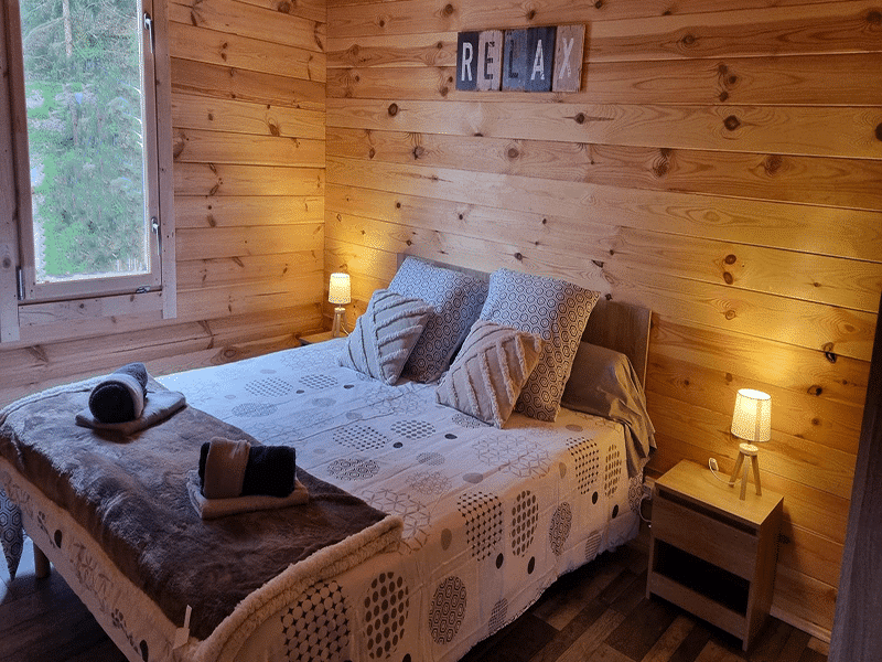 Chalet en bois chaleureux avec lit double et ambiance relaxante.