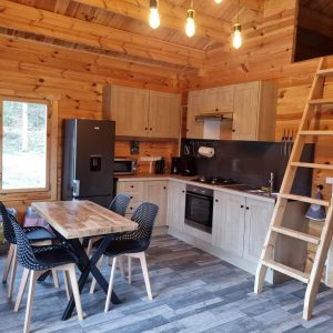 Cabane en bois en Bourgogne, avec cuisine moderne et échelle menant à une mezzanine.