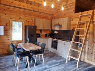 Cabane en bois en Bourgogne, avec cuisine moderne et échelle menant à une mezzanine.