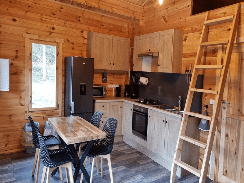 Chalet en bois avec cuisine moderne et coin repas chaleureux.