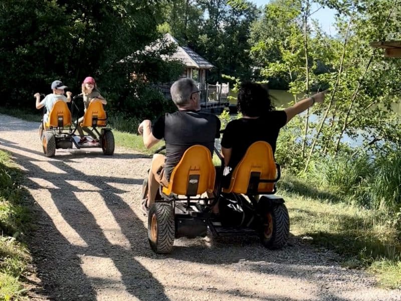 Location de cabanes au bord dun lac, avec des visiteurs en kart à pédales.