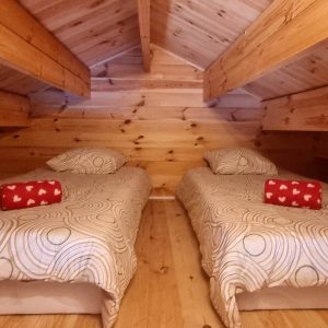 Chalet en bois avec deux lits simples et décorations chaleureuses en Bourgogne.