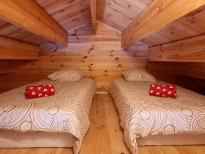 Chalet en bois avec deux lits simples et décorations chaleureuses en Bourgogne.