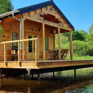Cabane en bois sur pilotis, entourée de verdure et reflétant dans leau.