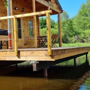 Cabane sur pilotis en Bourgogne, avec terrasse surplombant un étang paisible.