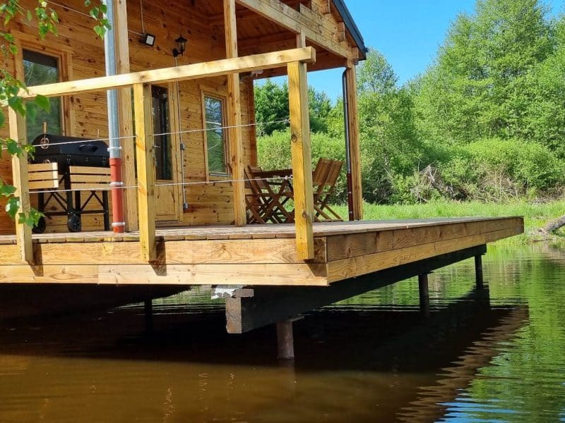 Chalet en bois au bord de leau, avec terrasse et vue sur la nature verdoyante.