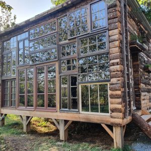 Cabane en bois avec de grandes fenêtres, entourée de verdure en Nouvelle-Aquitaine.