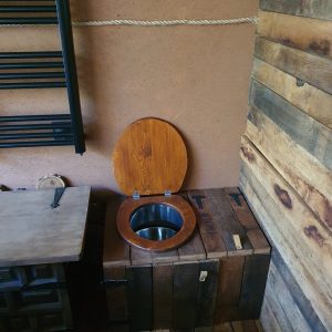 Hébergement insolite en Nouvelle-Aquitaine avec toilettes en bois sur un coffre rustique.