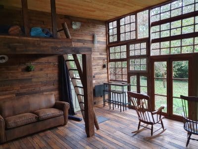 Hébergement insolite en bois avec mezzanine et grandes fenêtres sur la nature.