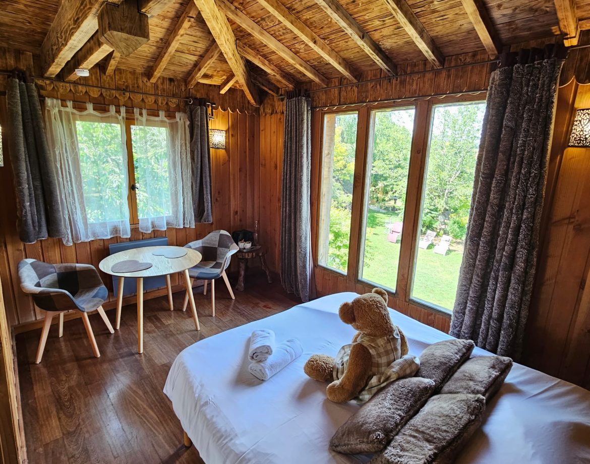 Cabane en bois cosy avec vue sur la nature, lit douillet et décor chaleureux.
