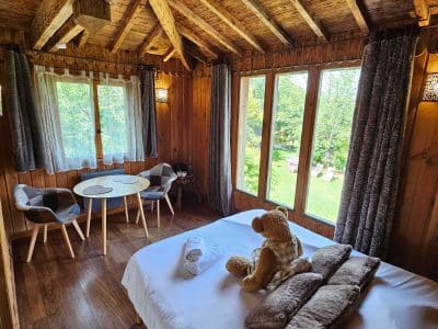 Cabane en bois cosy avec vue sur la nature, lit douillet et décor chaleureux.